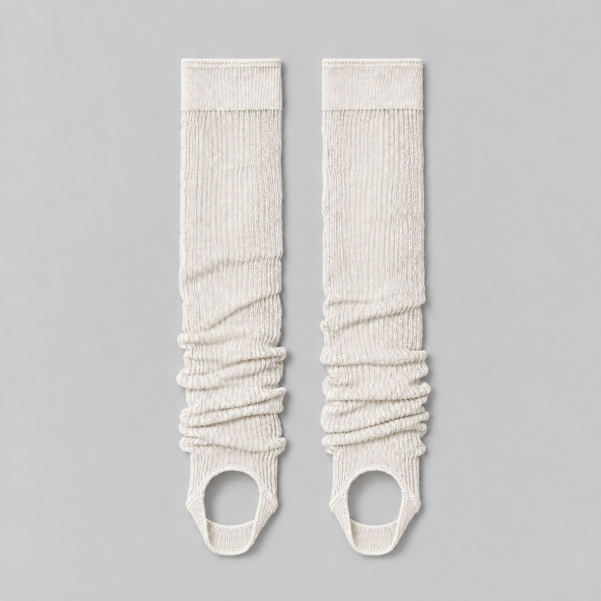 white ruched stirrup leg warmers laid flat on a pale background