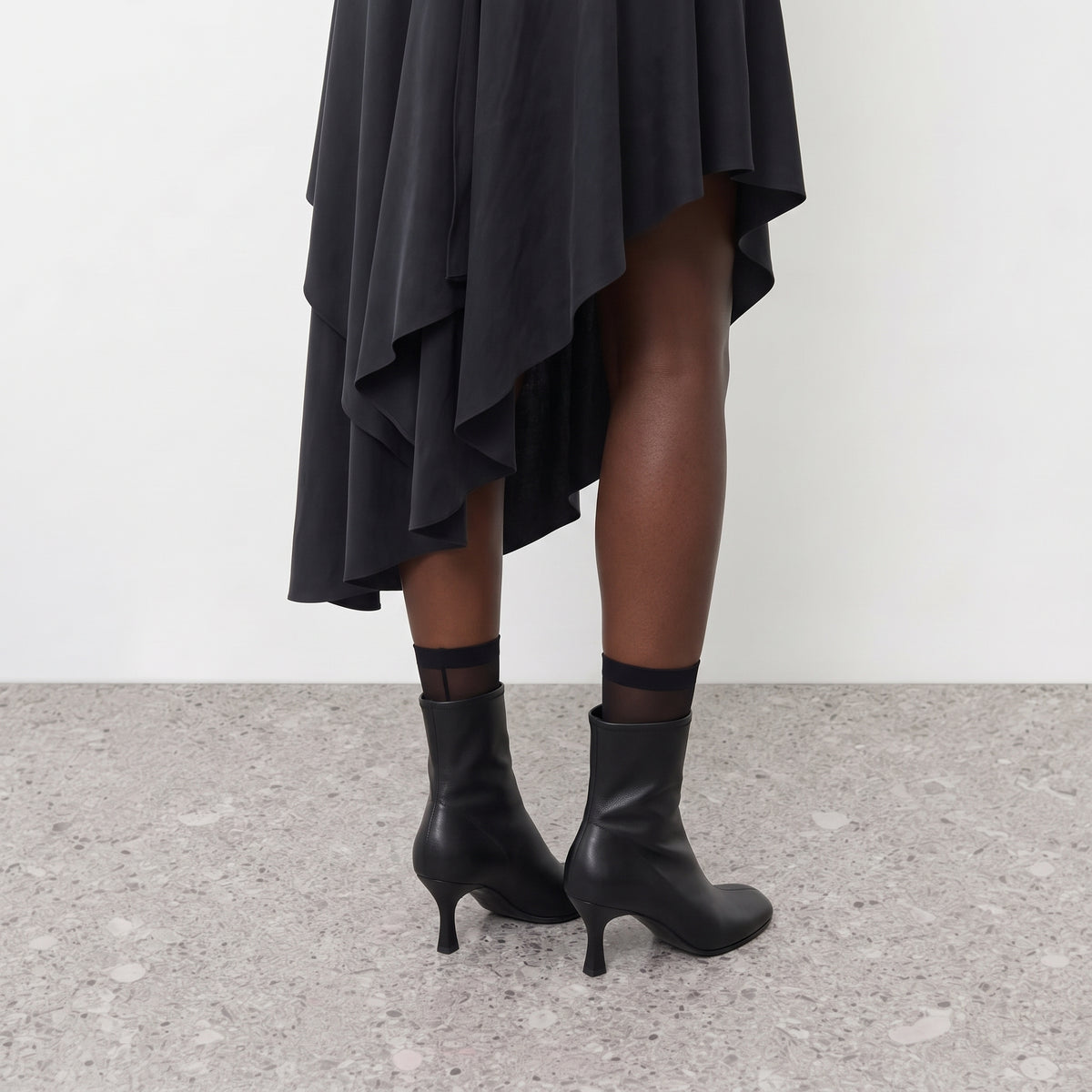 Close crop of the black boot heel and squared toe seen from behind