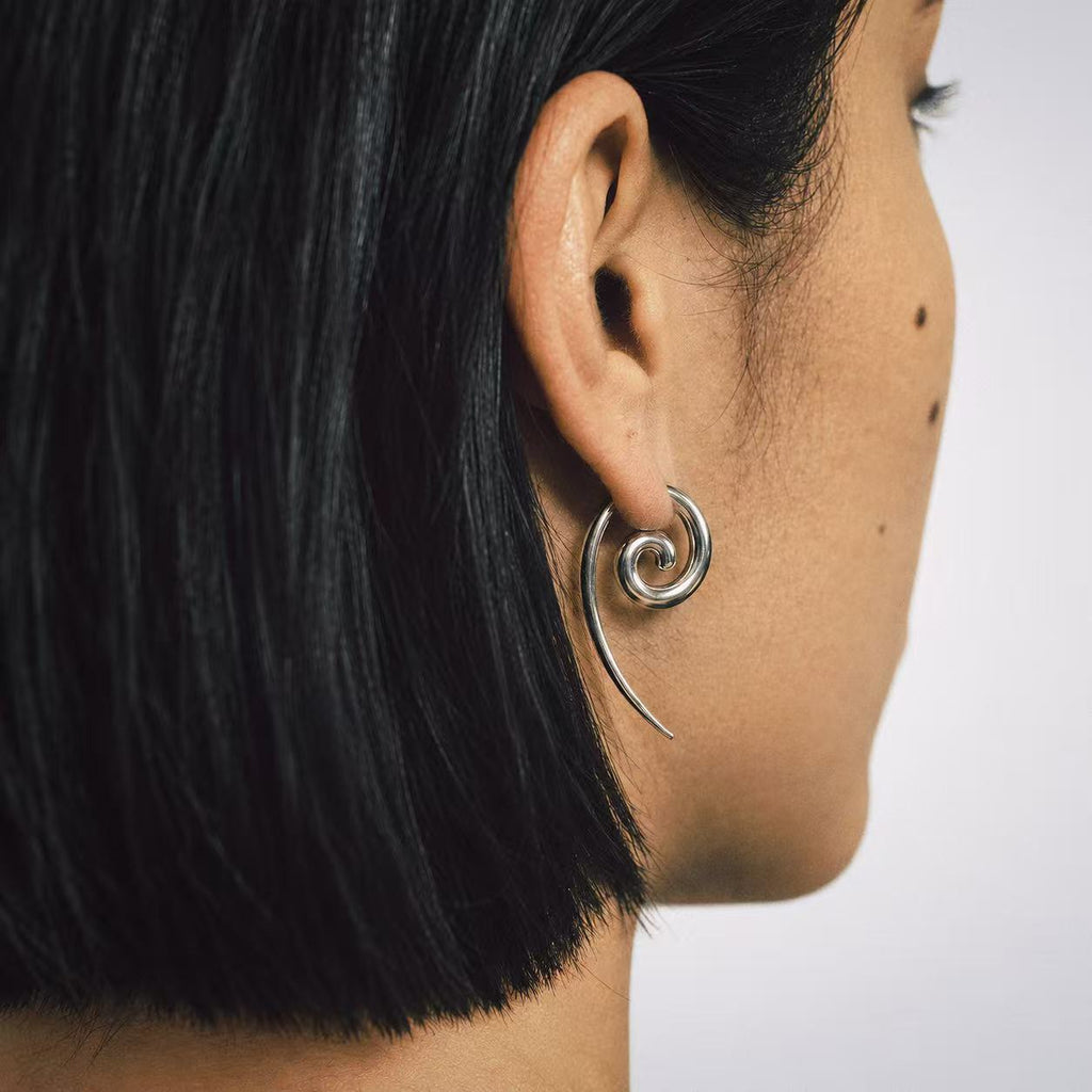 Model wearing the Spiral Coil Drop Earrings in a relaxed pose