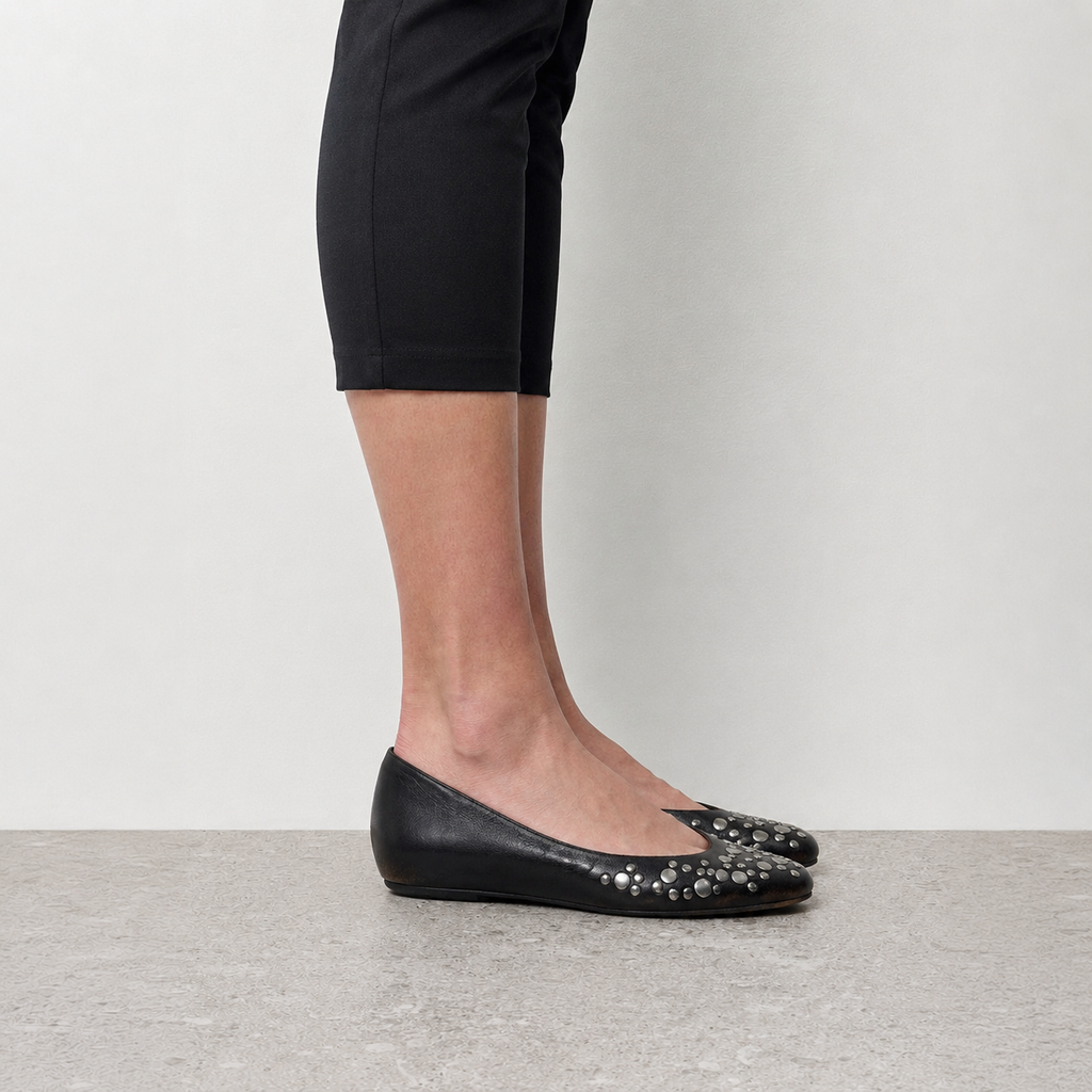 Side profile of a single black studded ballet flat showing the low wedged sole