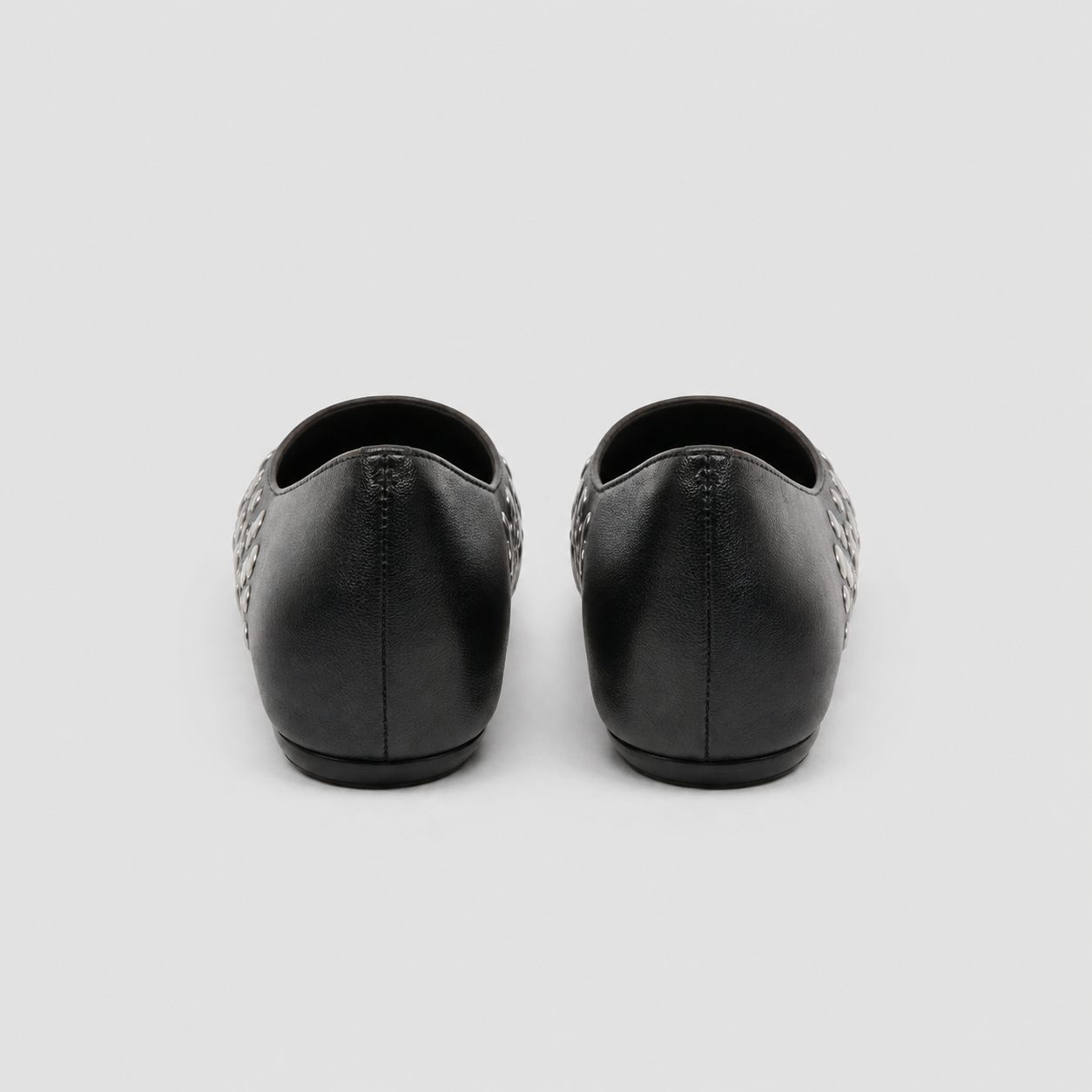 Rear view of black studded ballet flats showing plain heels and low wedged soles