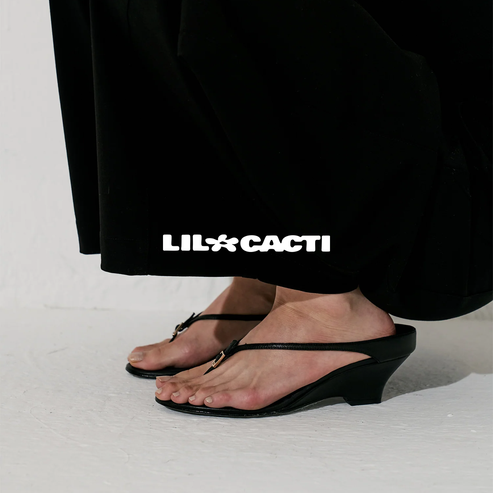 Black wedge sandals with sculptural sole and delicate metal toe detail by Lil Cacti