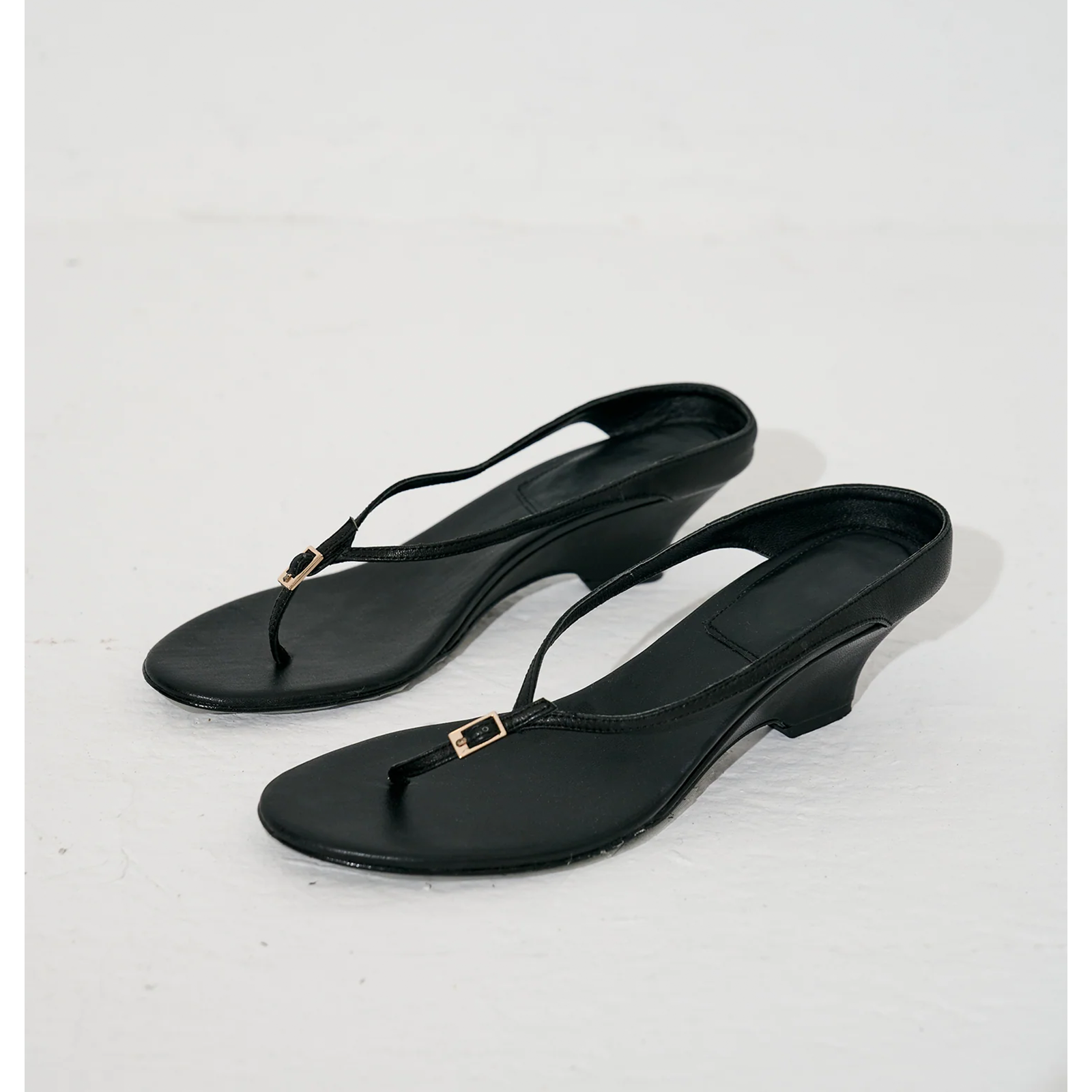 Black strappy sandals with wedge heel, side view on white background by lil cacti