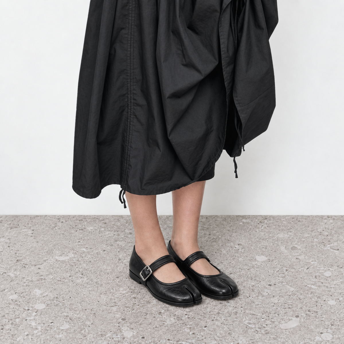 Model wearing black split toe mary jane flats with a silver buckle strap