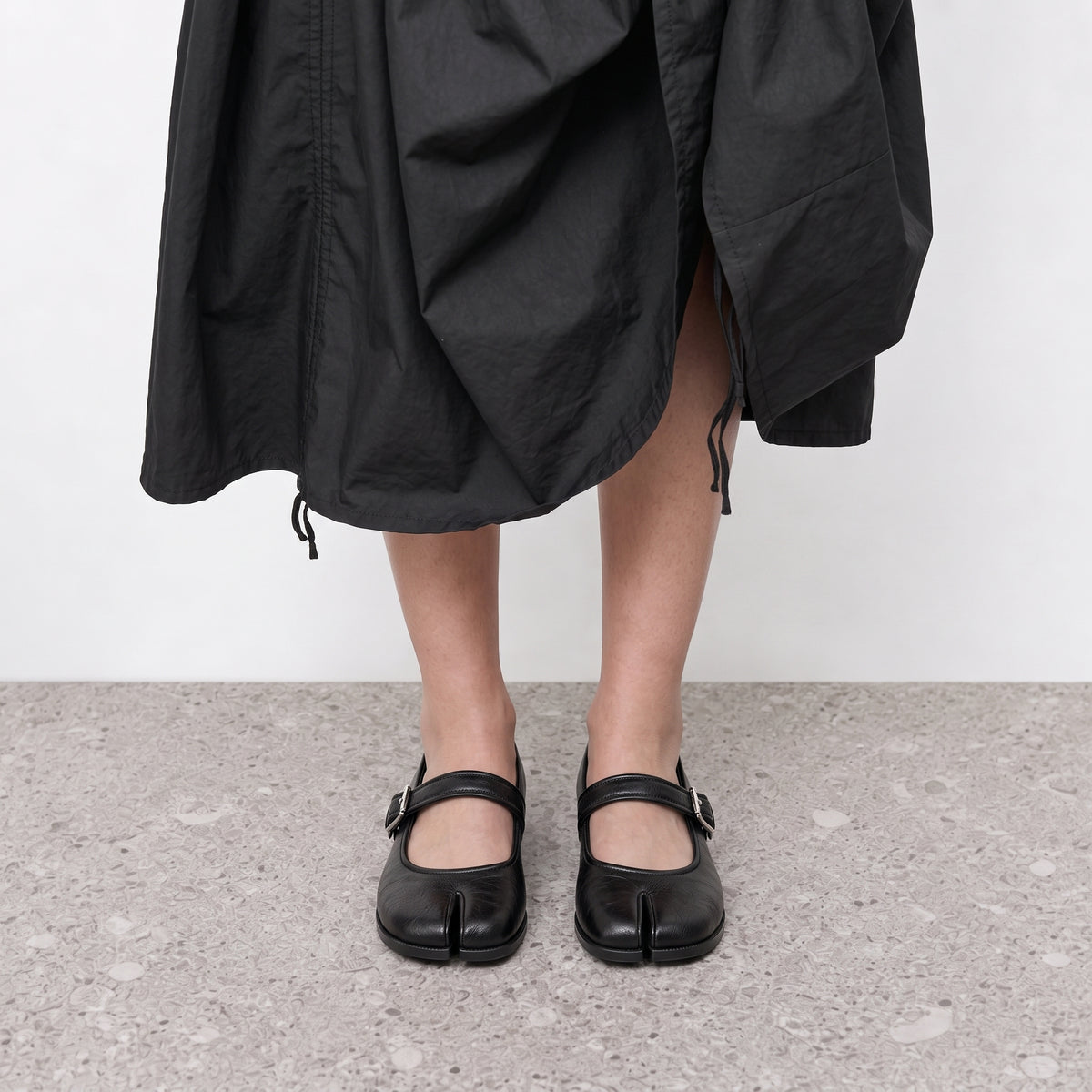 Front view on the foot of black tabi mary janes showing the divided toe and strap