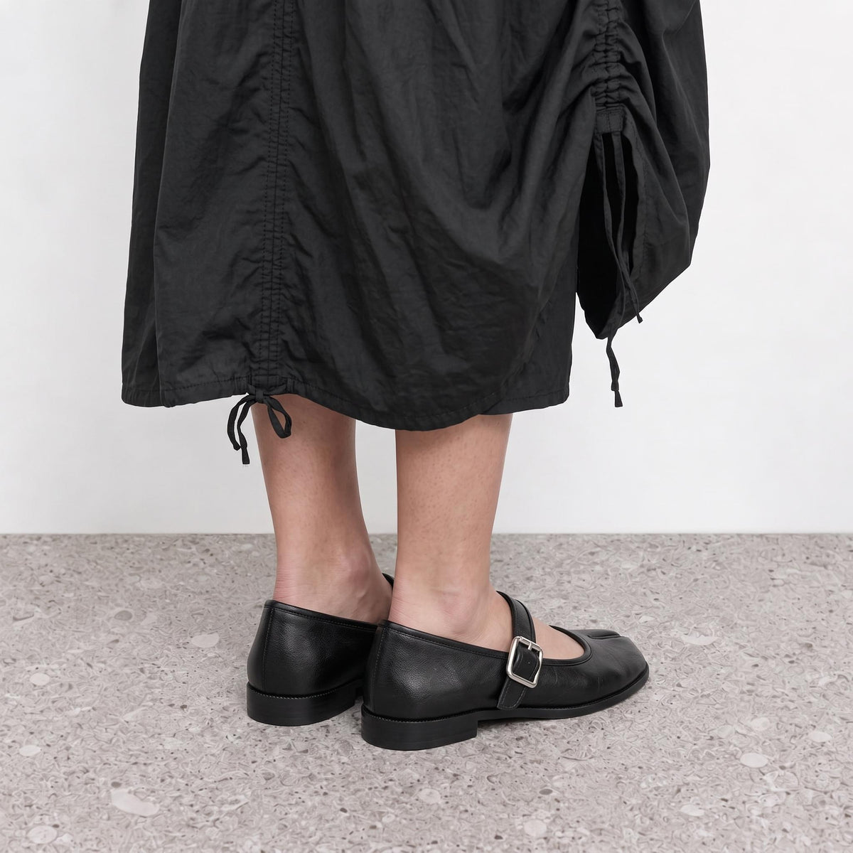 Model standing in Lil Cacti black tabi mary jane flats on a stone floor