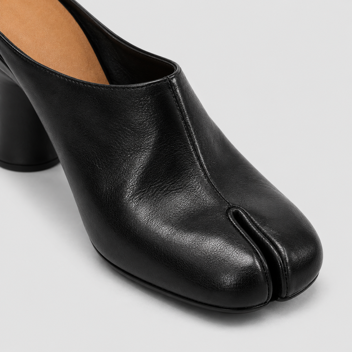 Close-up of a black tabi mule showing the block heel and tan insole