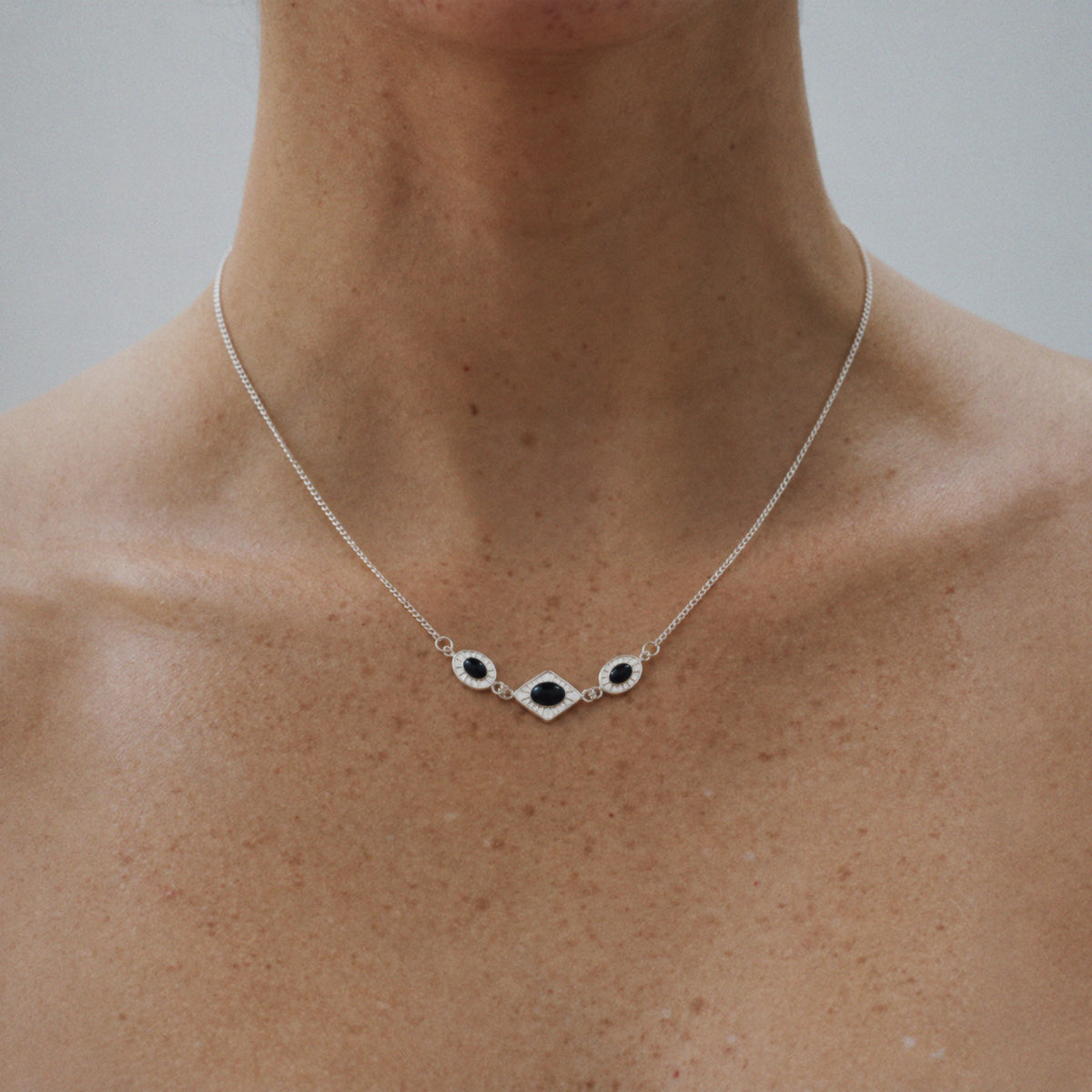 Model wearing Lil Cacti Triad Art Deco Station Necklace, close crop on the detail