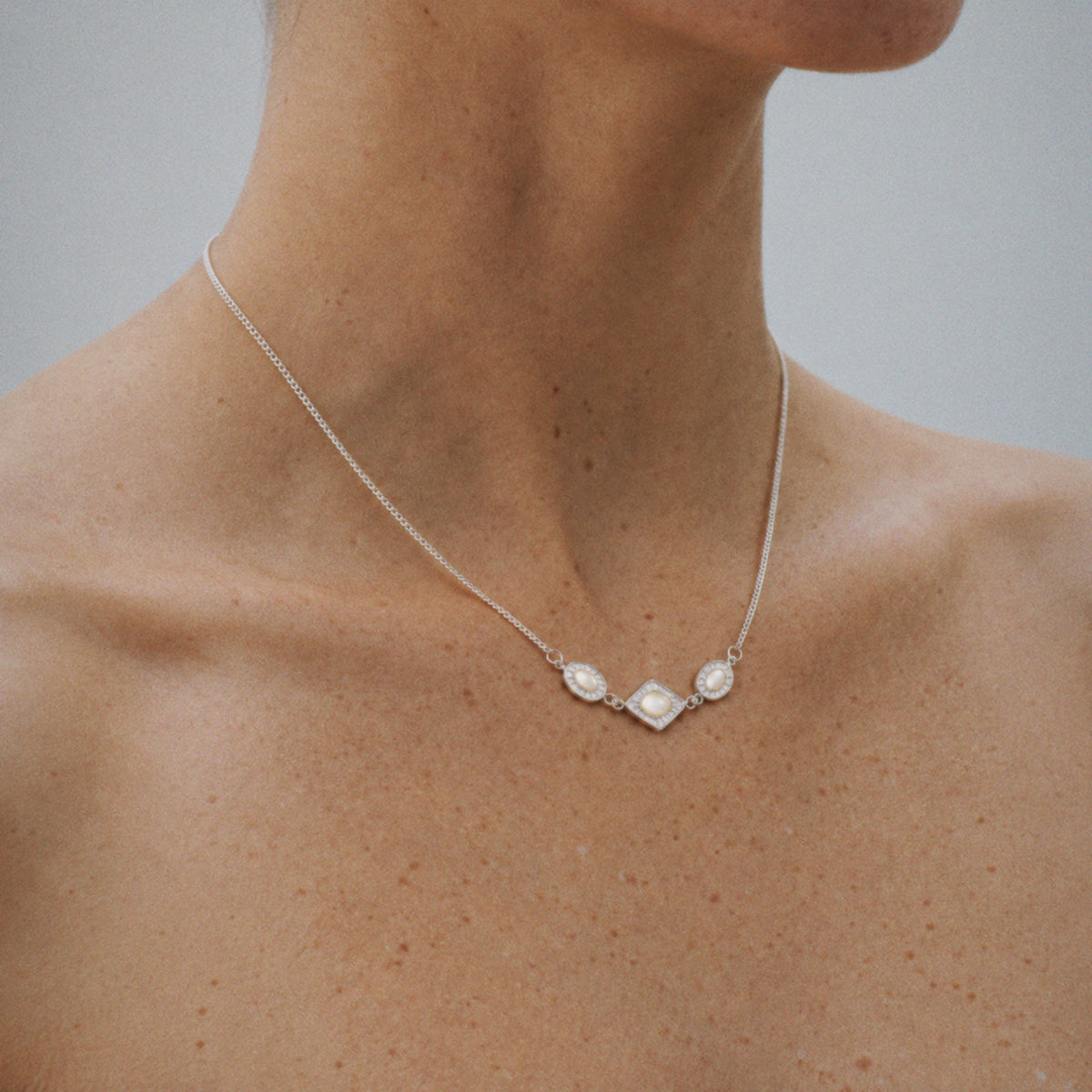 Model wearing the Triad Art Deco Station Necklace, back of the ear visible