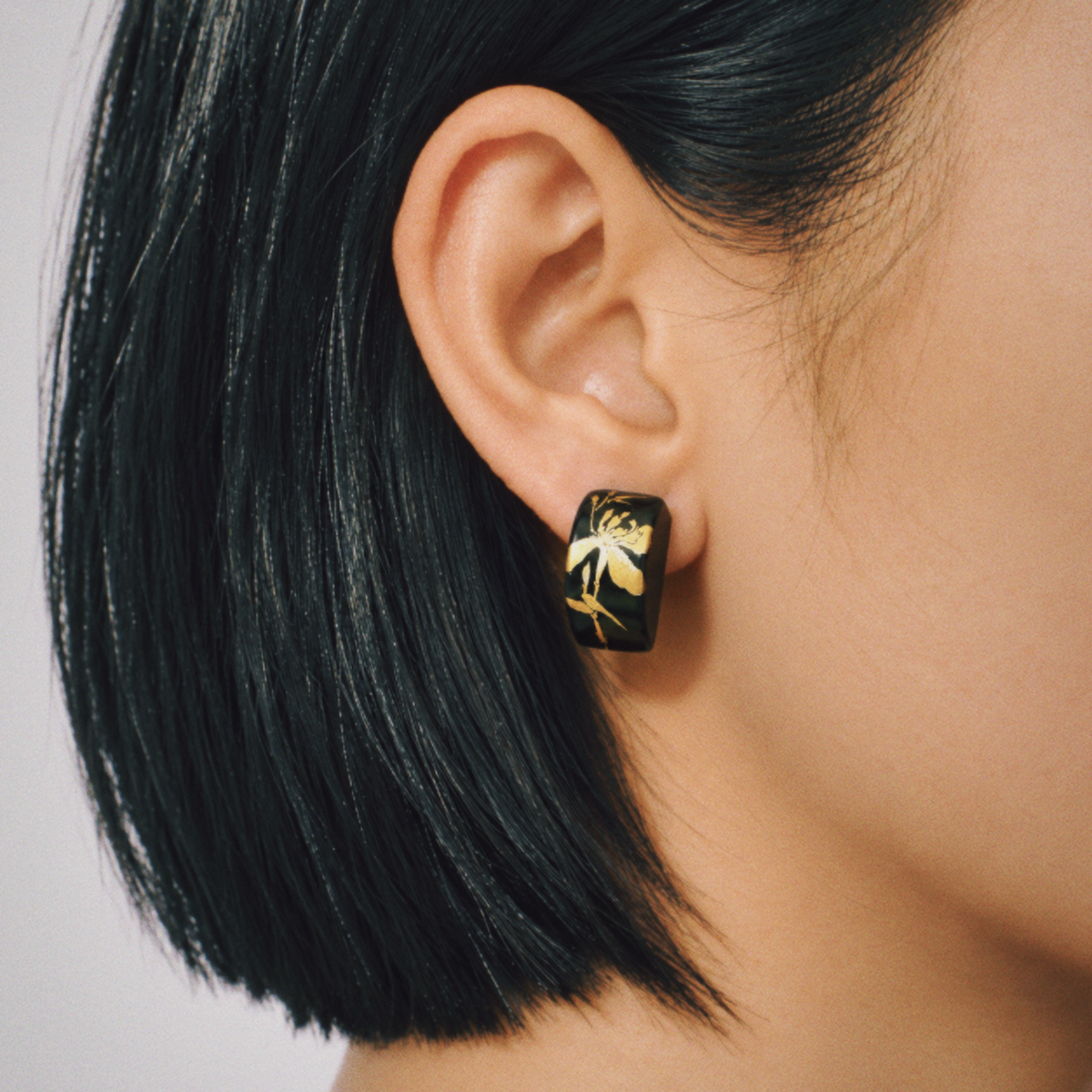 Black iris floral rectangle earrings shown worn beside the face