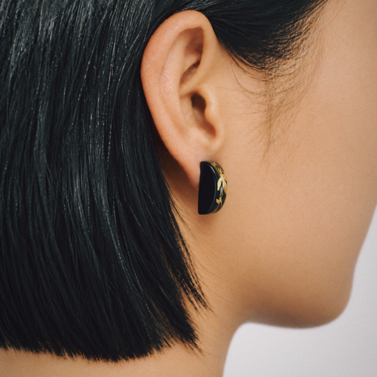 Side view of black iris floral earrings shown on an ear