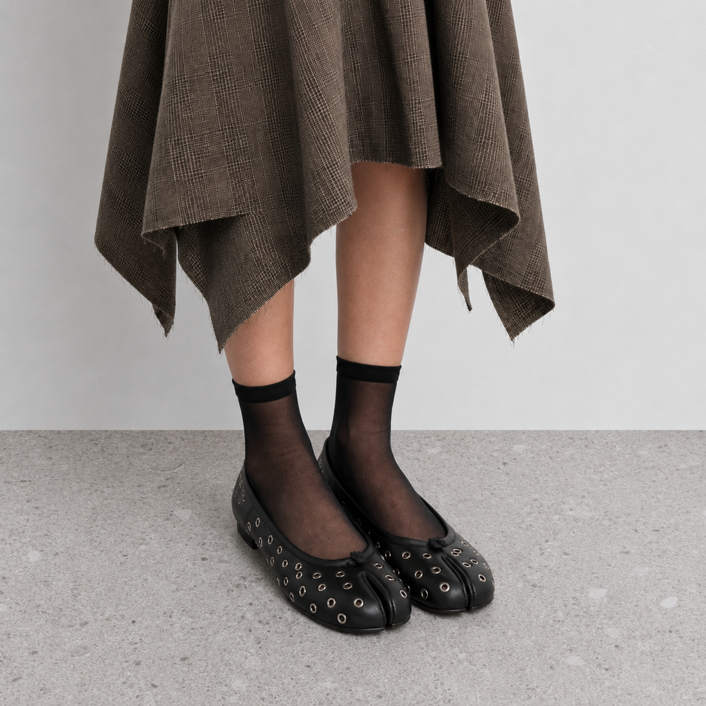 Model in Lil Cacti eyelet tabi flats, sheer black socks and draped brown garment