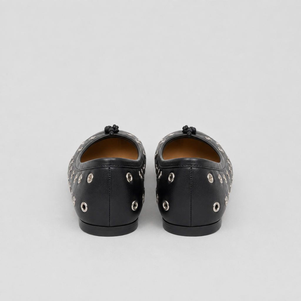 Back view of black eyelet flats, silver grommets on heel sides, plain center seam