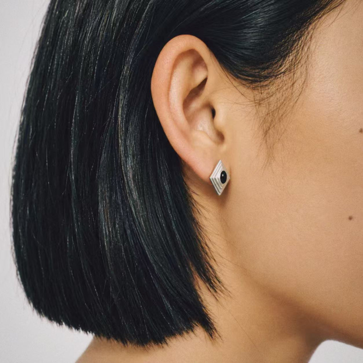 Model wearing the Ziggurat Stepped Stud Earrings from a side angle, black stud earrings