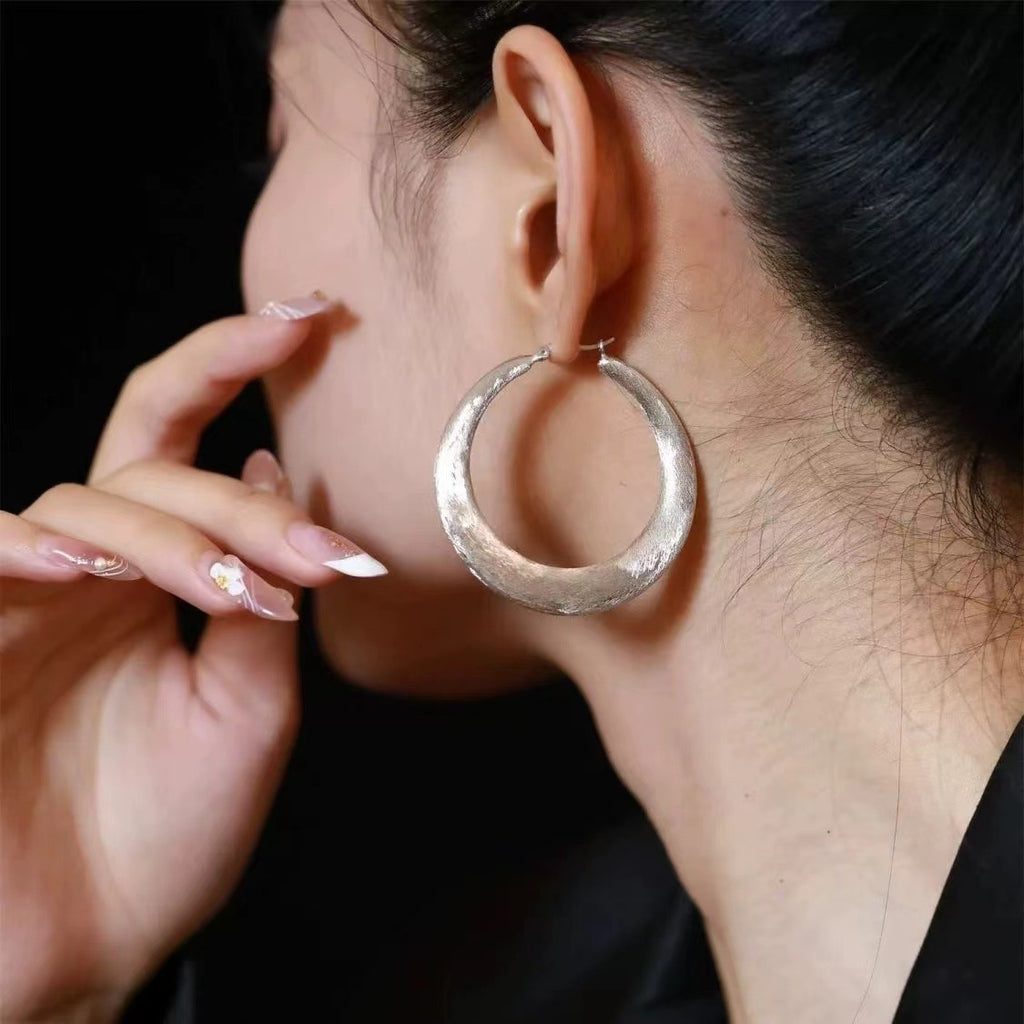 Close-up of the Tide Hammered Hoop Earrings, showing the finish and shape up close